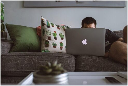 A man sitting on the sofa while working because of lower back pain